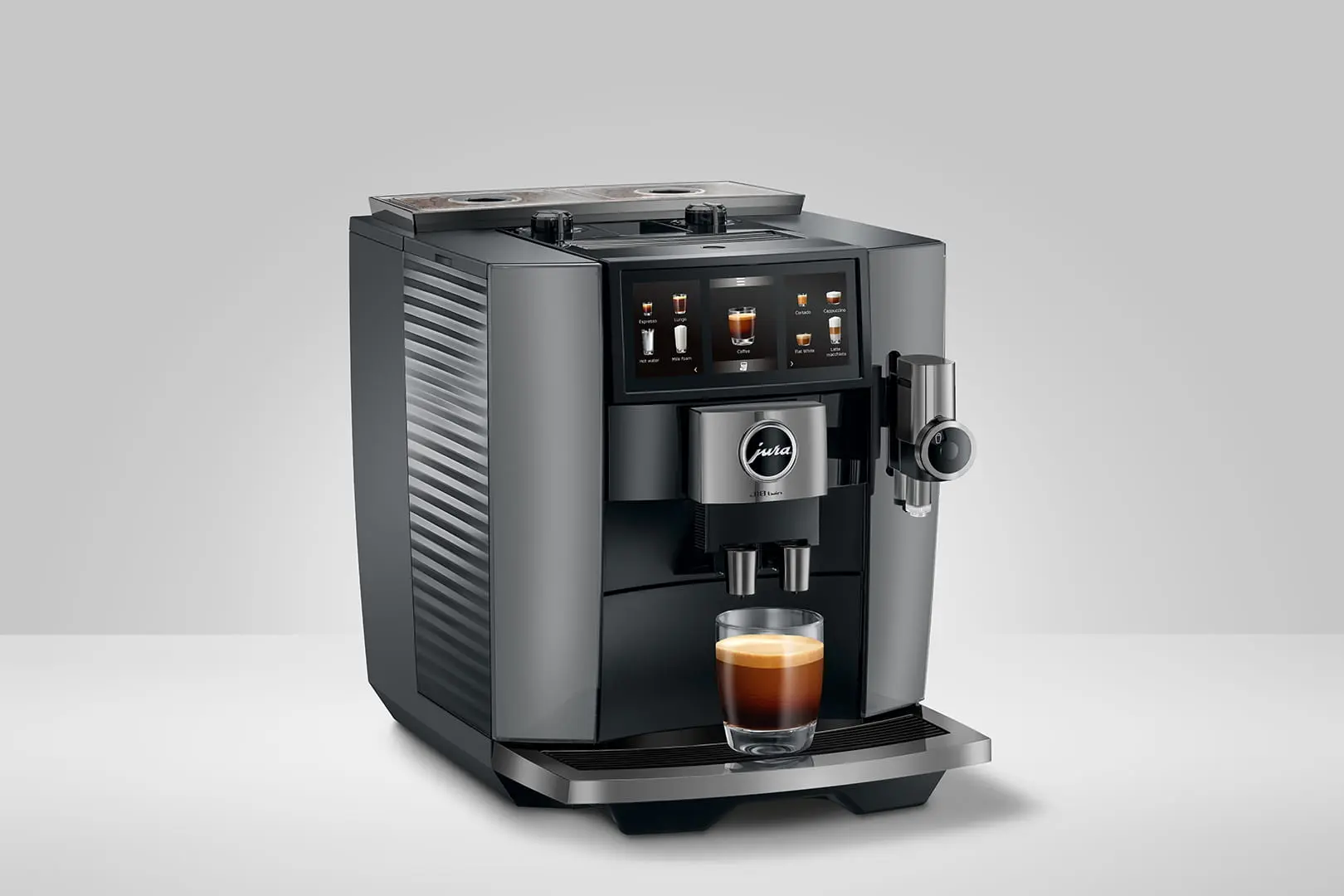 Vue panoramique de la JURA J10 twin Diamond Onyx (SA) avec son écran tactile activé, montrant les deux bacs à grains et un café fraîchement coulé.