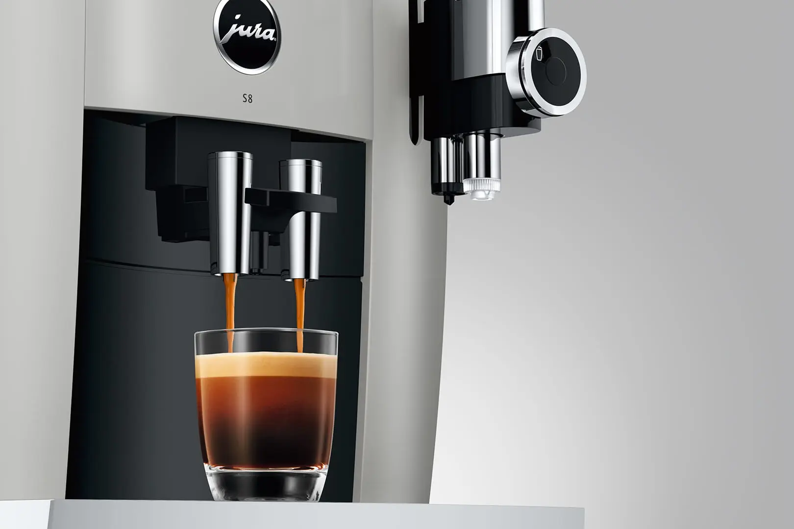 Écoulement d'un espresso sur une machine JURA S8 Platine avec une crème parfaite, mettant en avant les buses chromées et la buse de mousse fine Pro.