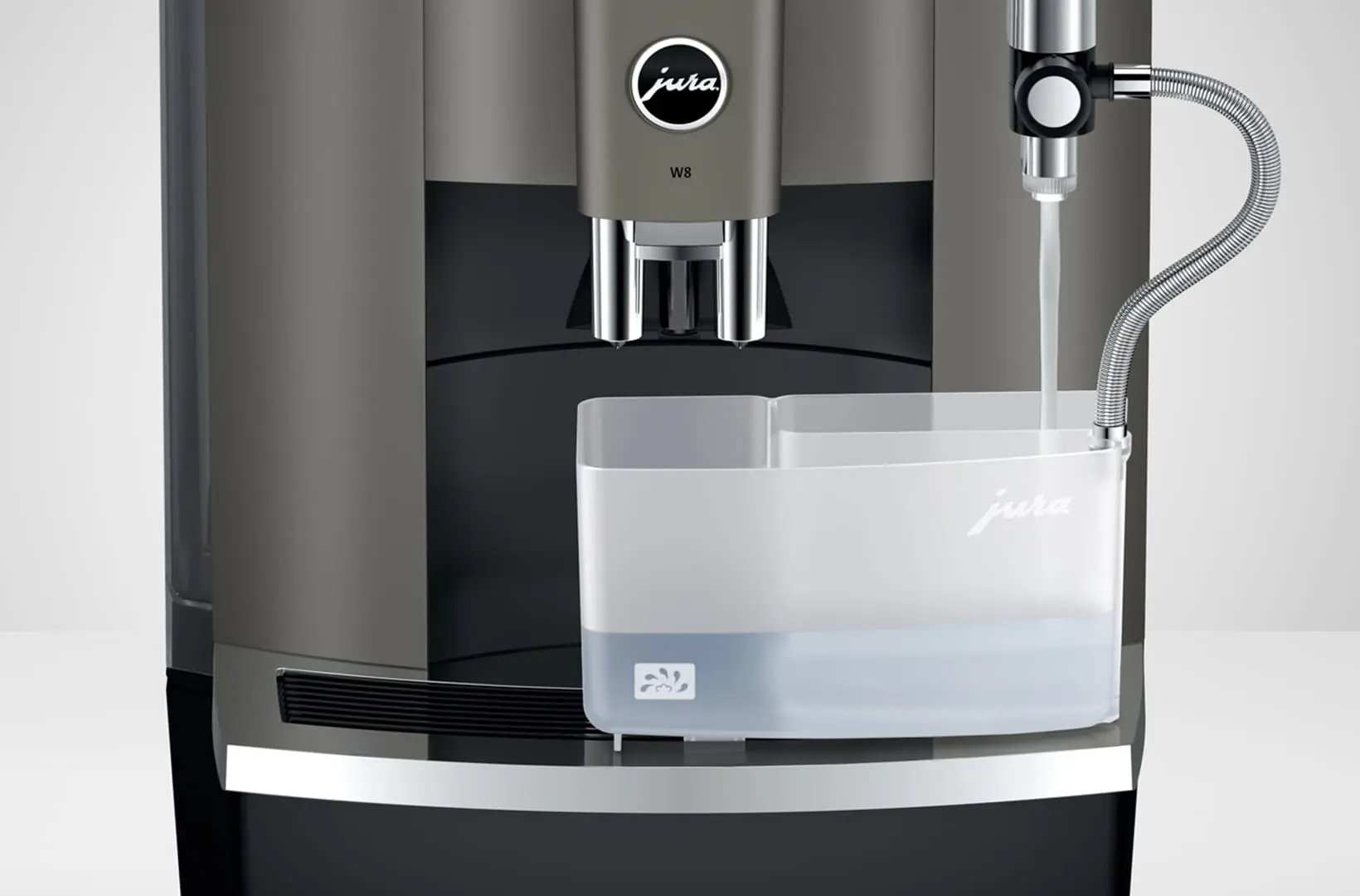 Étape de nettoyage du système de lait de la JURA W8 Dark Inox avec le récipient à double compartiment et l'écoulement d'eau chaude.